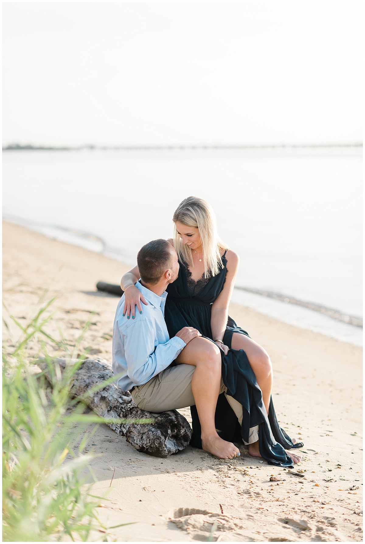 A beach front engagement photo featuring a flowy navy blue dress and a grassy beach at Terrapin Park in Stevensville, Maryland by Maryland Wedding Photographer Megan Bennett Photography