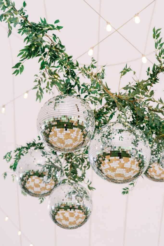 Up close of the tented ceiling decor of disco balls and greenery